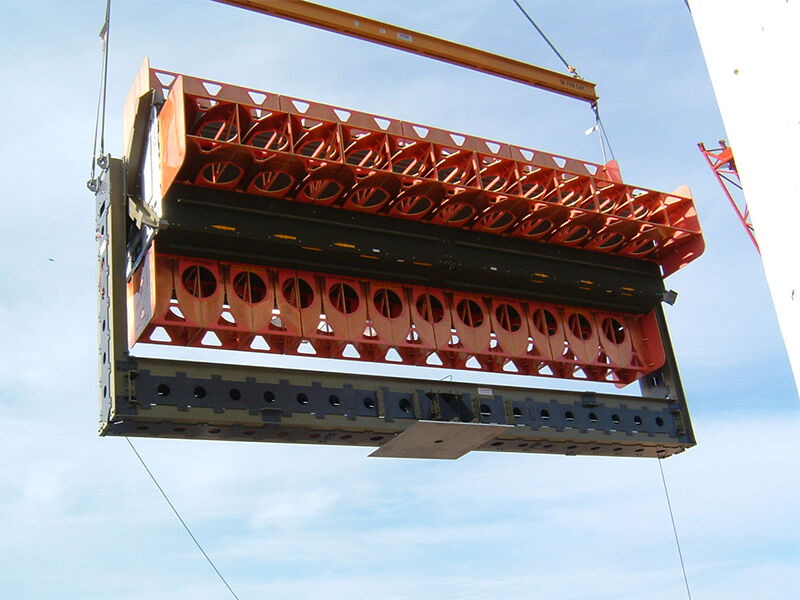 The low dielectric large antenna test fixture, loaded with additional equipment, is being raised by a crane for placement. 
